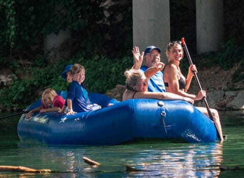 family in raft smile for the camera during their trip with River Ranch Resort Noel, Missouri in a large blue tube