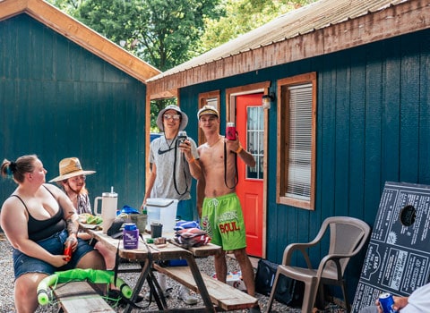 group of friends enjoy a little party outside a cabin after floating on the Elk River with River Ranch Resort in Noel, Missouri