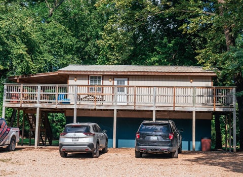 cars parked outside cabin with wrap around porch for rent near River Ranch Resort in Noel, Missouri