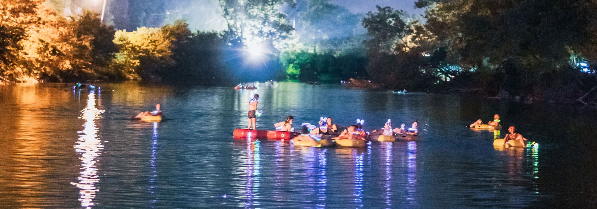 rafters and rafts glow in the water as the sun goes down for the glow float on Elk River with River Ranch Resort Noel, Missouri